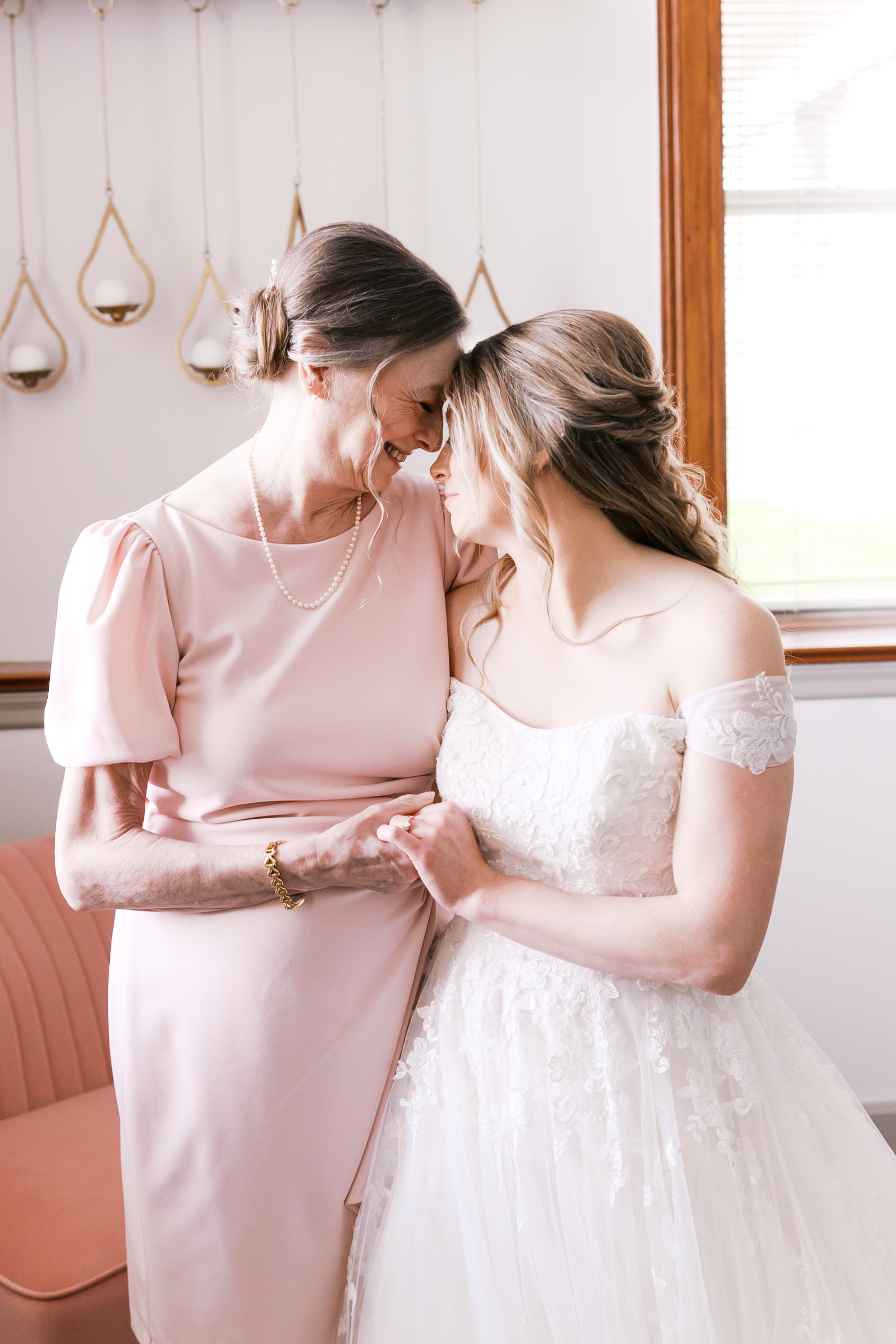 Bride and her mother sharing a tender forehead embrace while getting ready for the wedding.