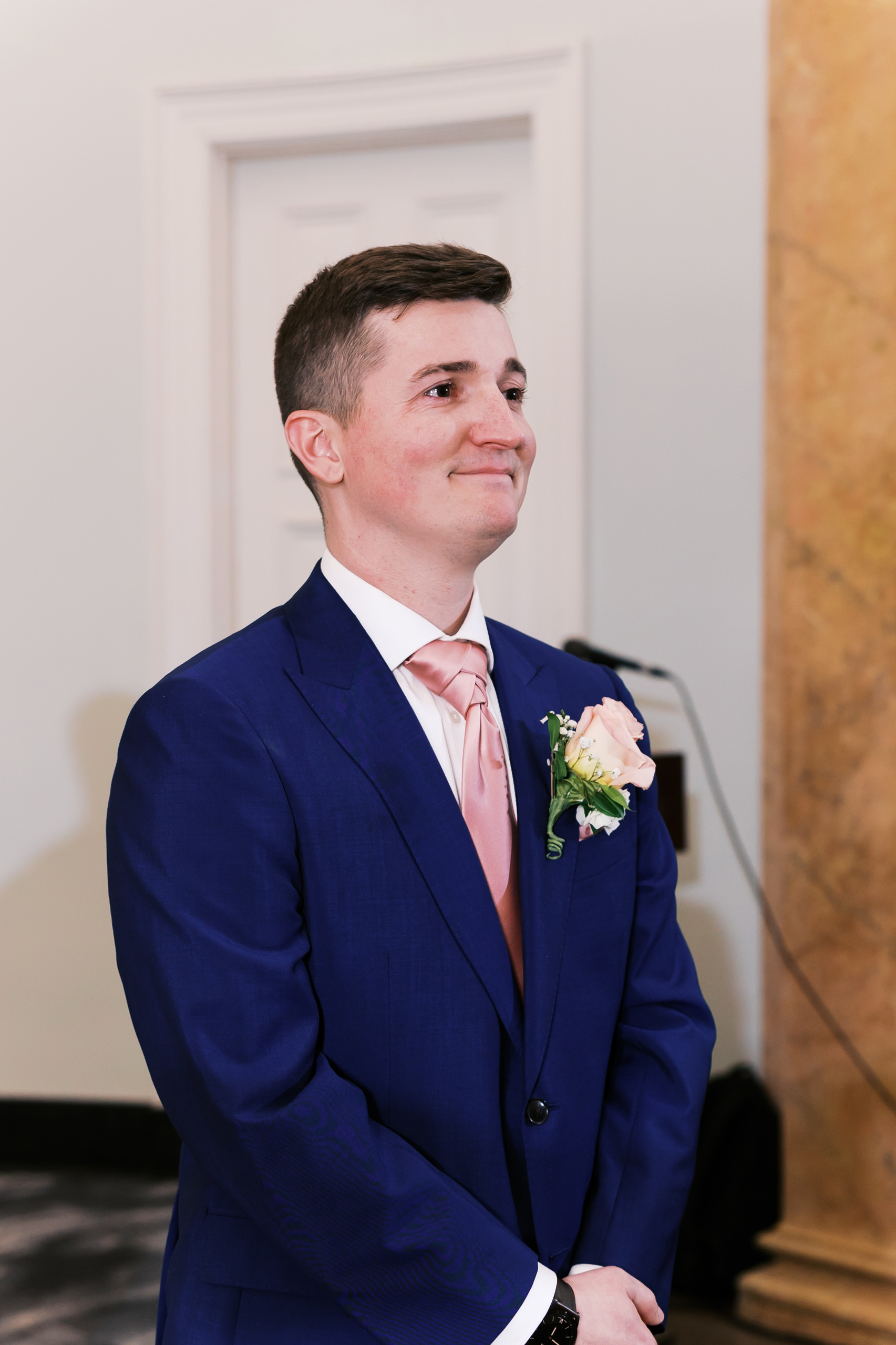 Groom smiling while waiting at the altar before the wedding ceremony begins.