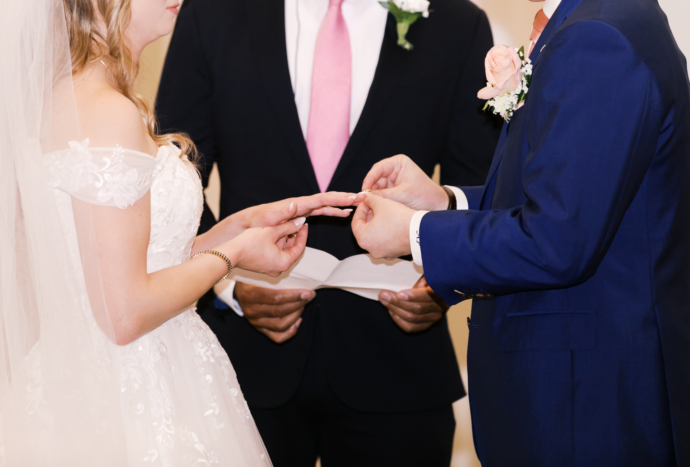Groom placing a wedding ring on the bride's finger during the ceremony.