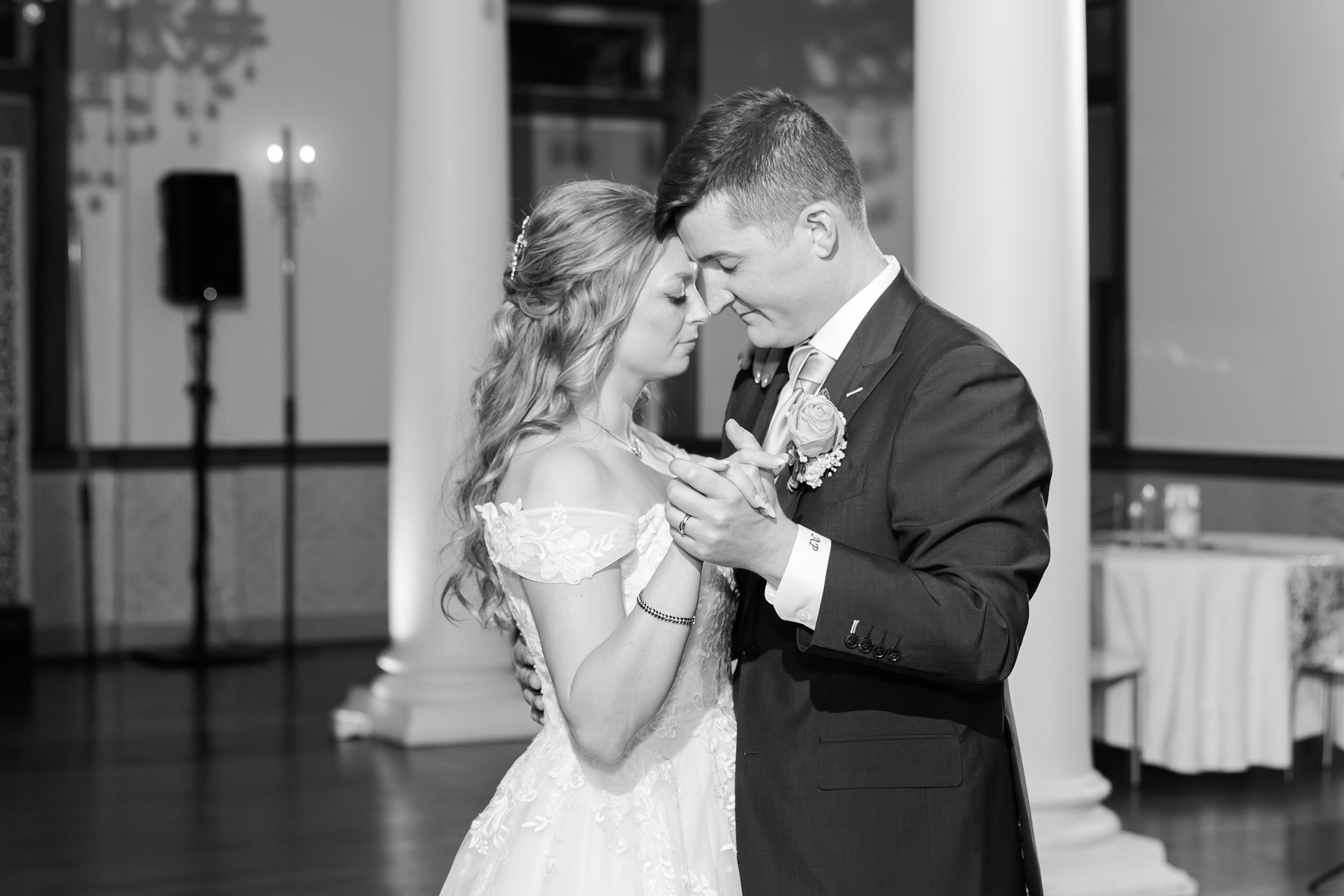 Bride and groom share a quiet slow dance in a black-and-white wedding reception portrait.