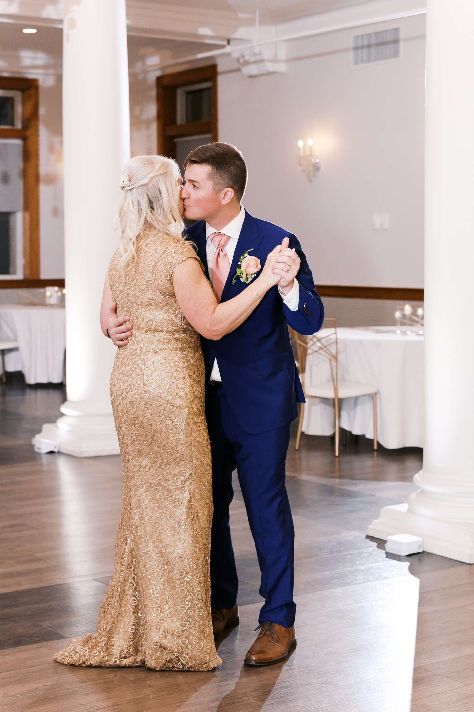 Groom shares a dance with his mother during the wedding reception in an elegant ballroom.