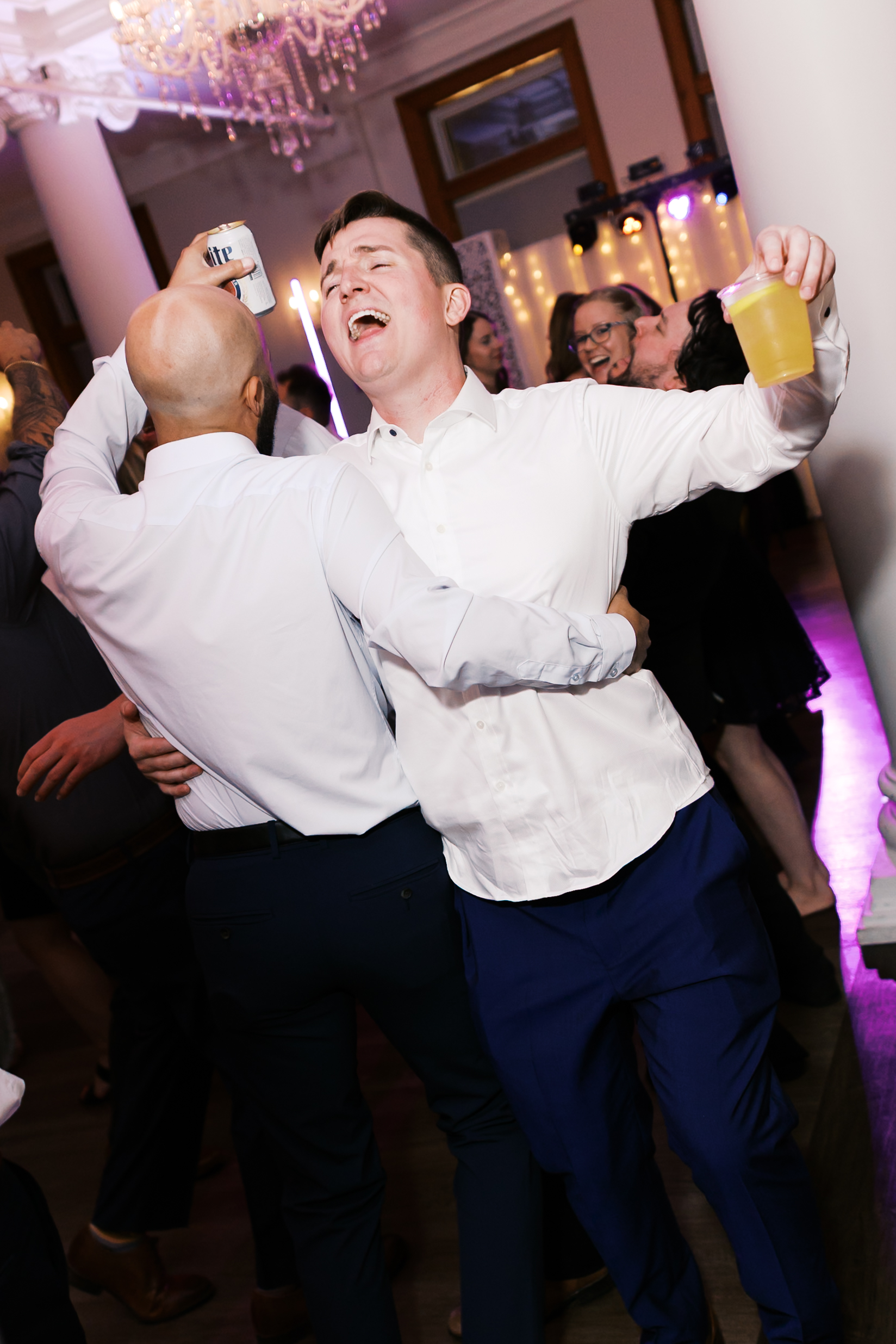 Groom sings along while celebrating with guests on the dance floor during the wedding reception.
