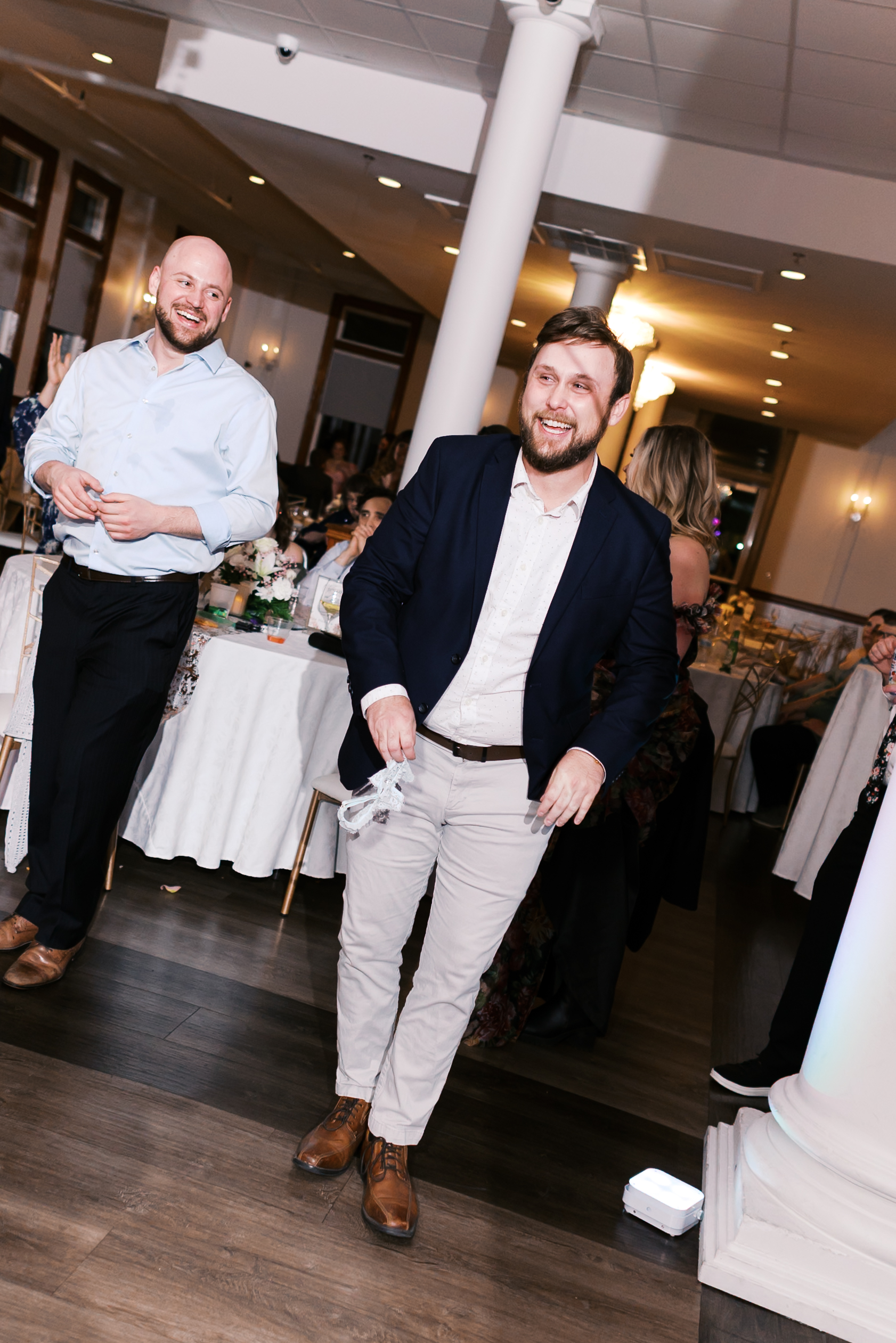 Wedding guest smiles while holding the bridal garter after catching it during the lively reception celebration.