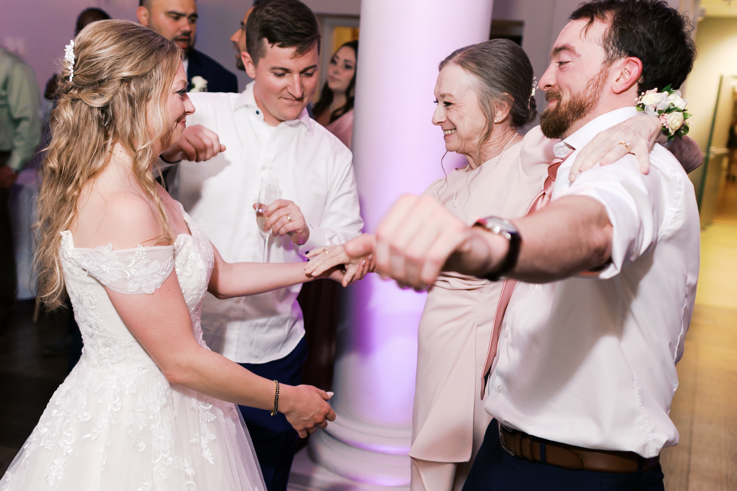Bride dances with family members during the wedding reception as guests gather around the dance floor.