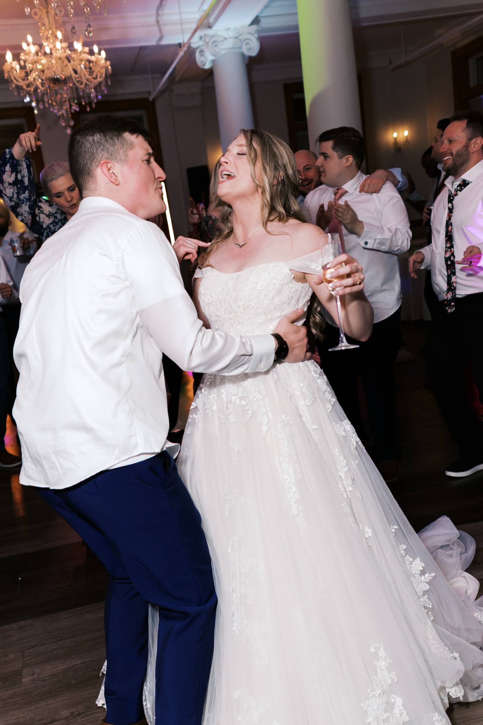Bride and groom dancing during the wedding reception as guests gather around the dance floor.