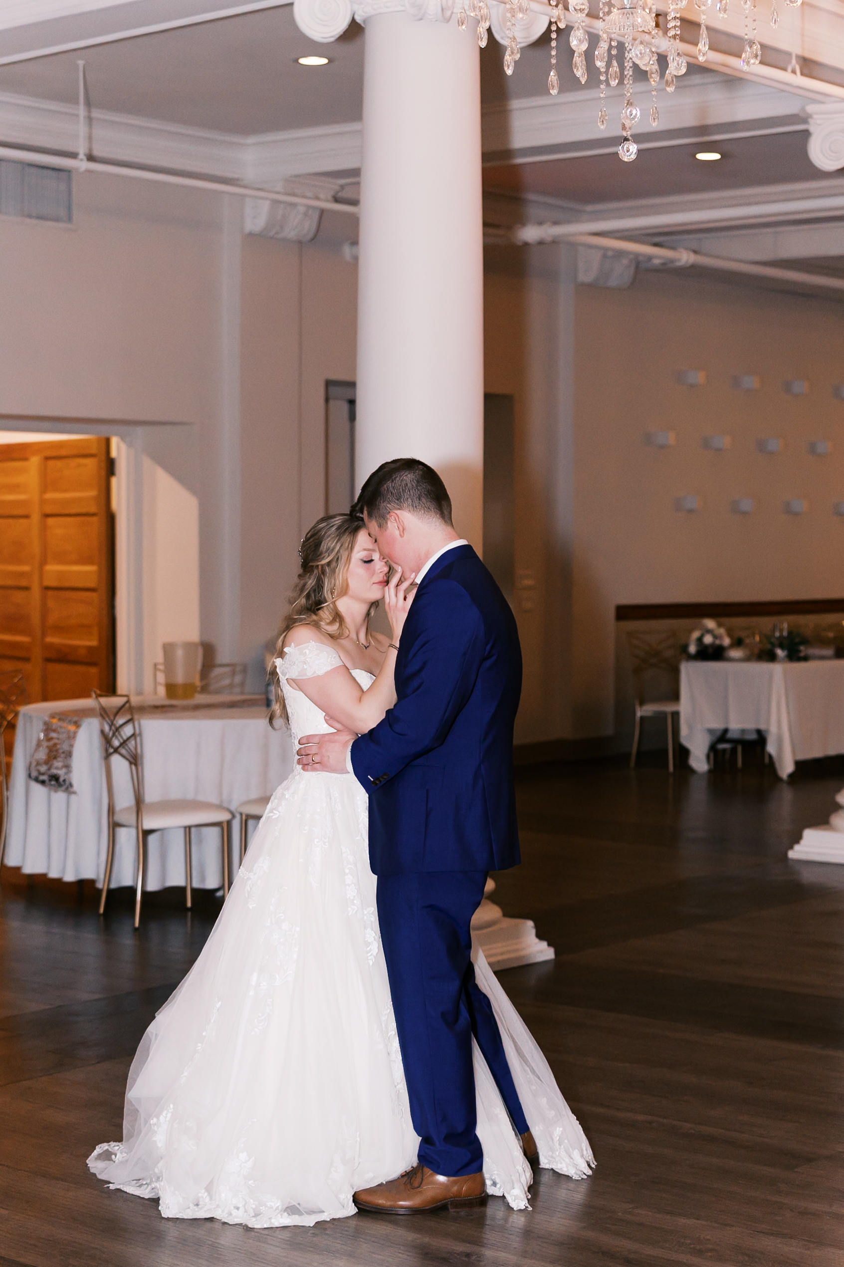 Bride and groom share a quiet dance in the reception hall surrounded by elegant columns and soft lighting.