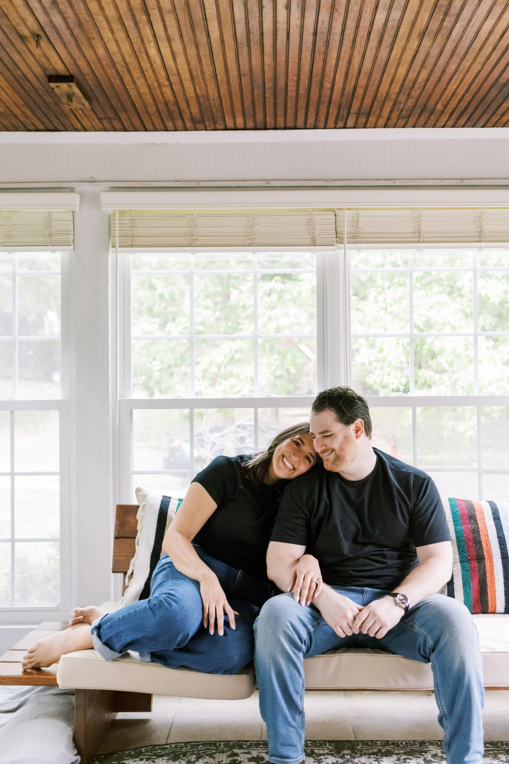 Engaged couple cuddling on a couch at home.