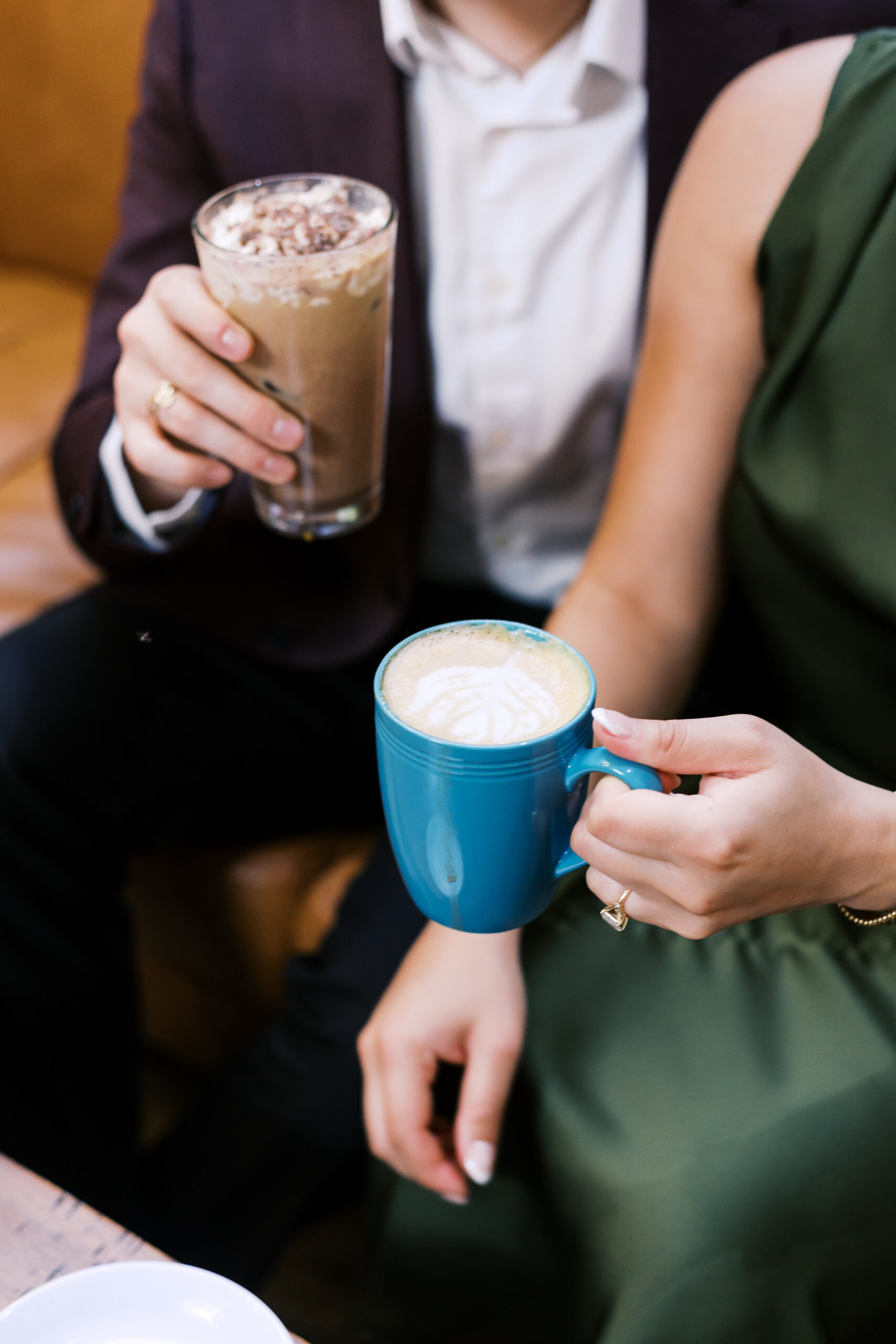 Close-up of an engaged couple holding coffee drinks together at Café Corazón
