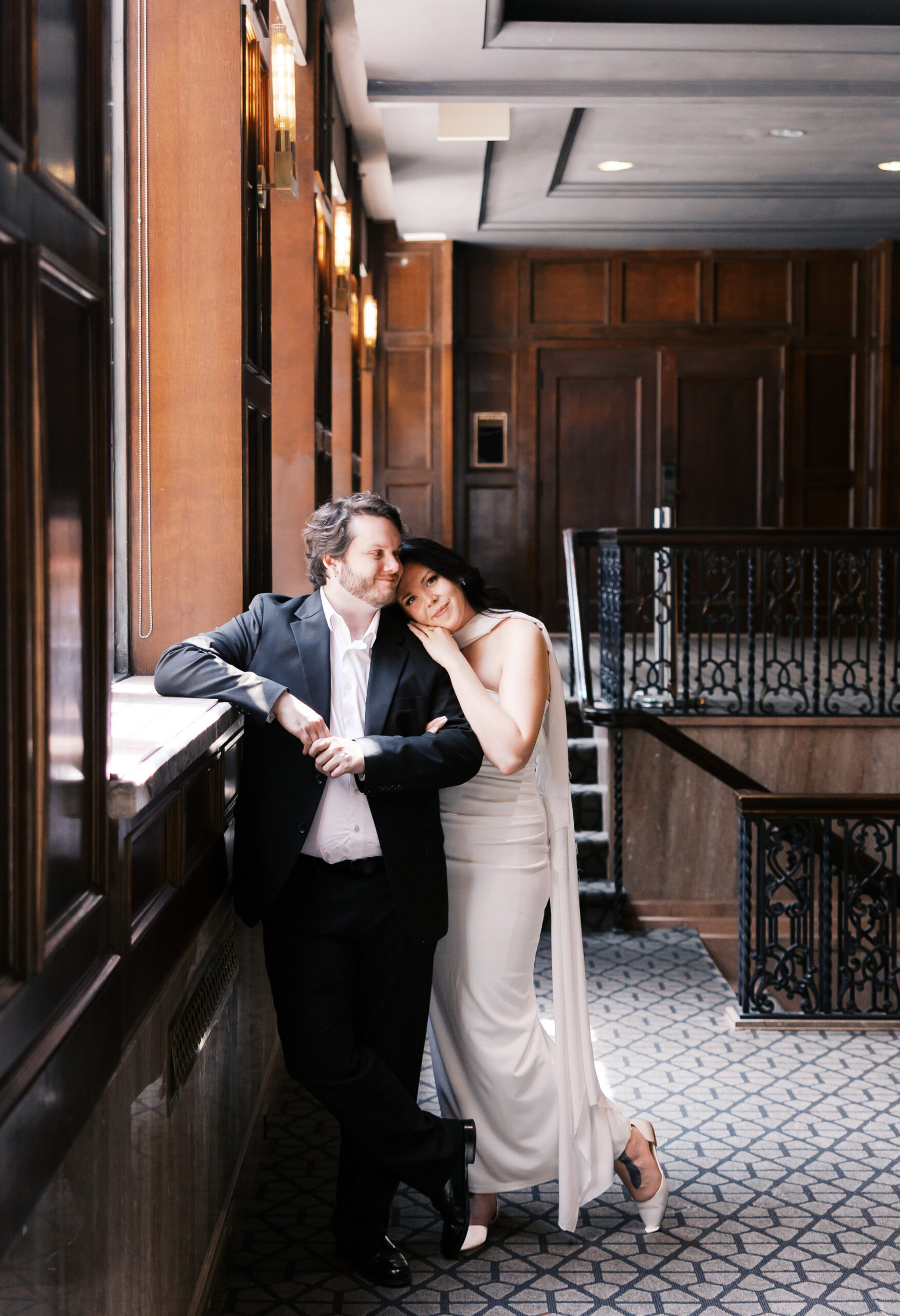 Engaged couple leaning together in a wood-paneled hallway at Hotel Phillips.