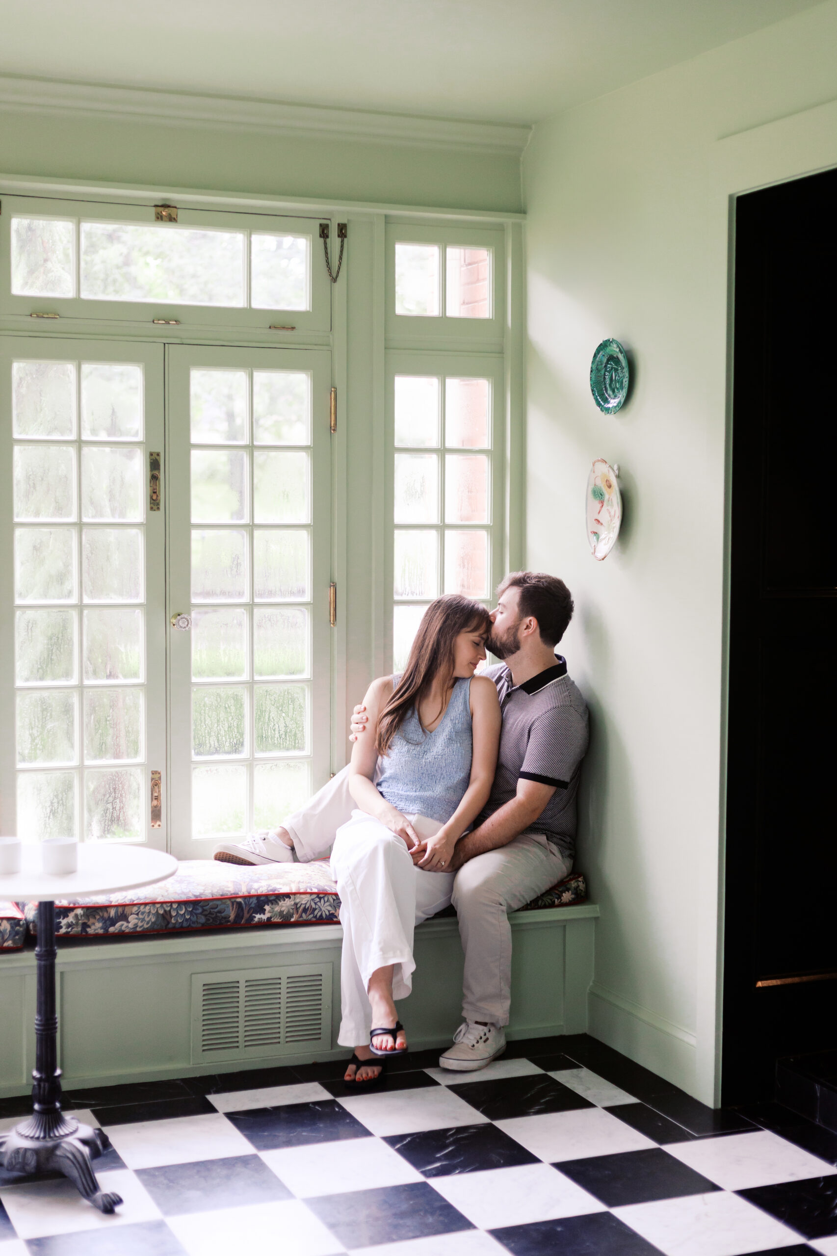 Engaged couple sitting close on a window bench at The Truitt in Kansas City