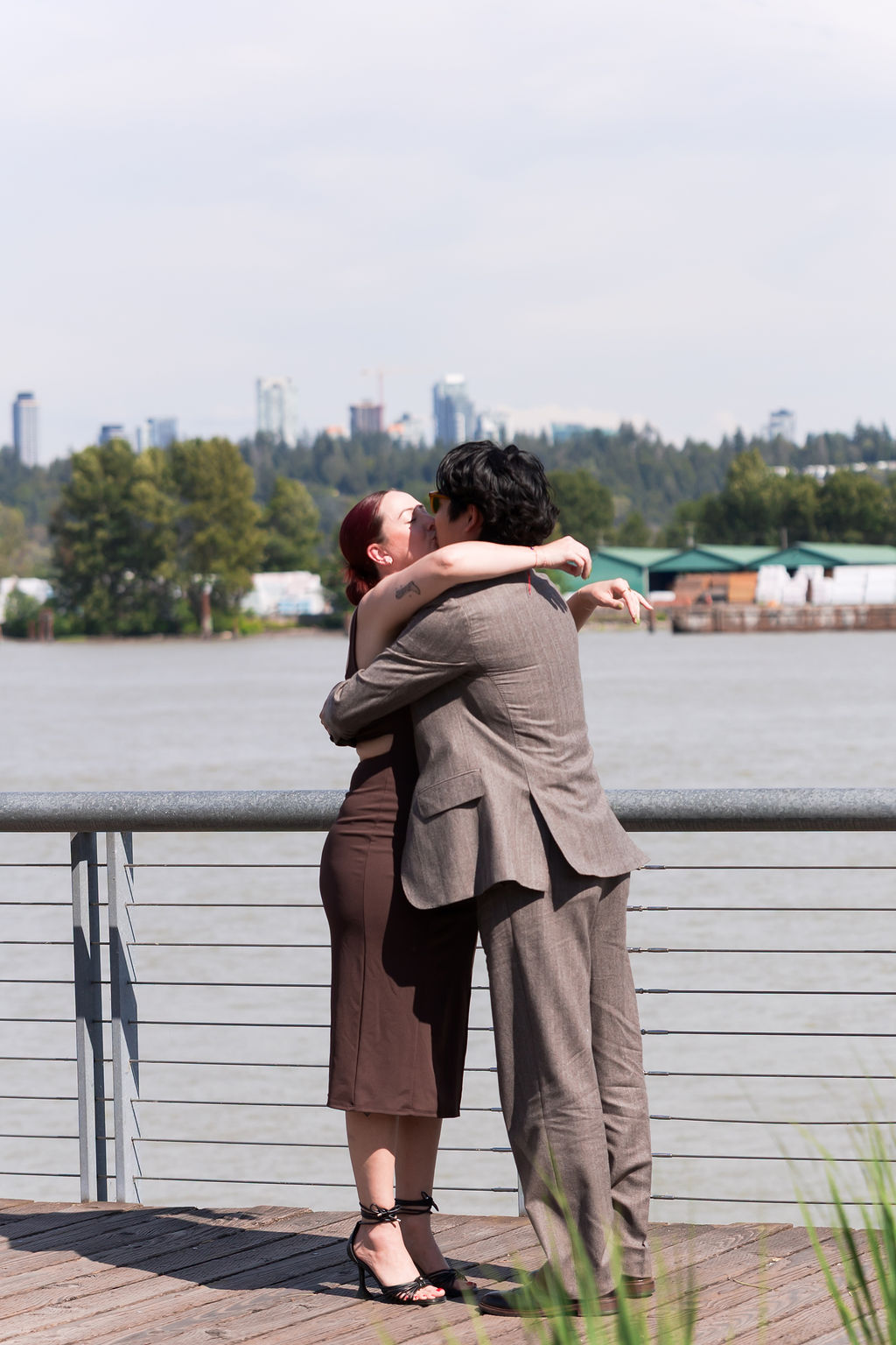 The newly engaged couple embraces after the proposal on the waterfront.