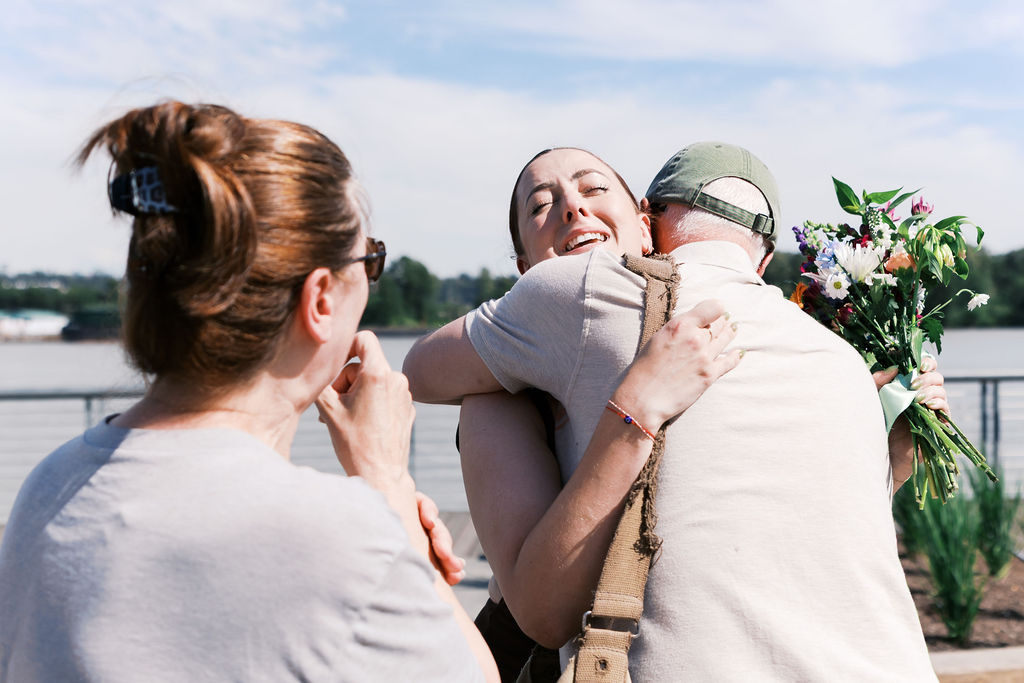 A newly engaged person hugs a family member while holding a bouquet of flowers.