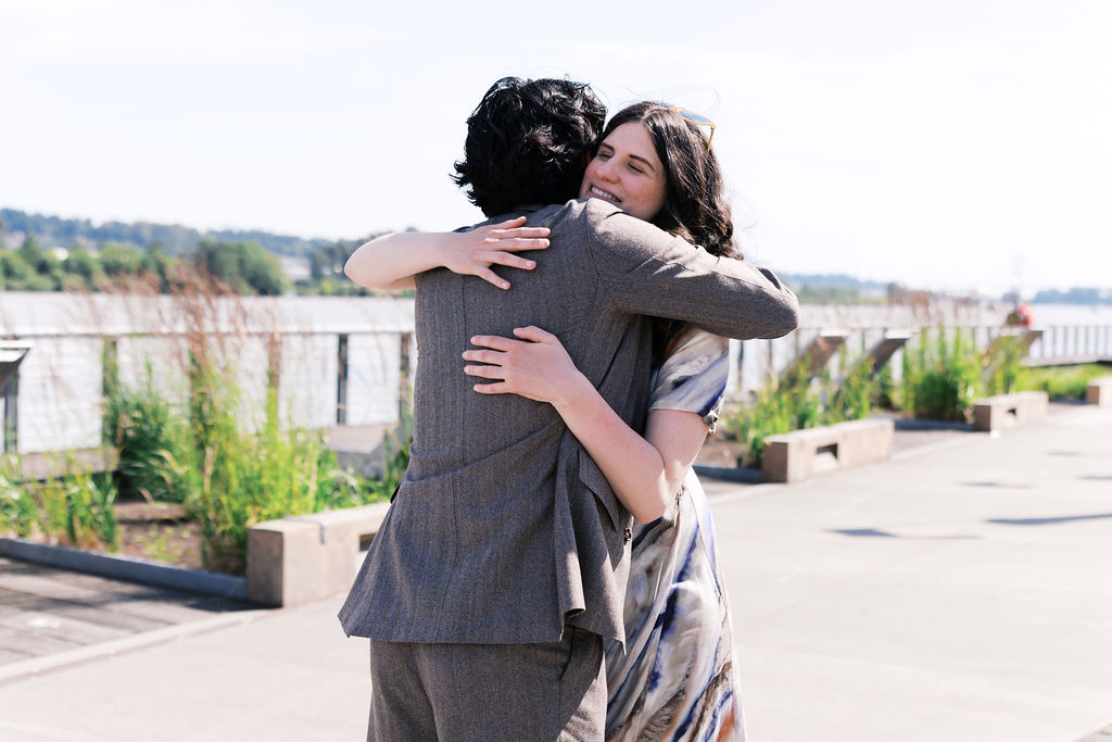 One partner hugs a friend as loved ones gather after the proposal.