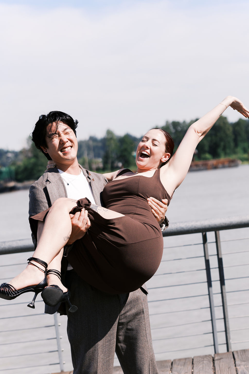 The couple laughs as one partner carries the other after the proposal.