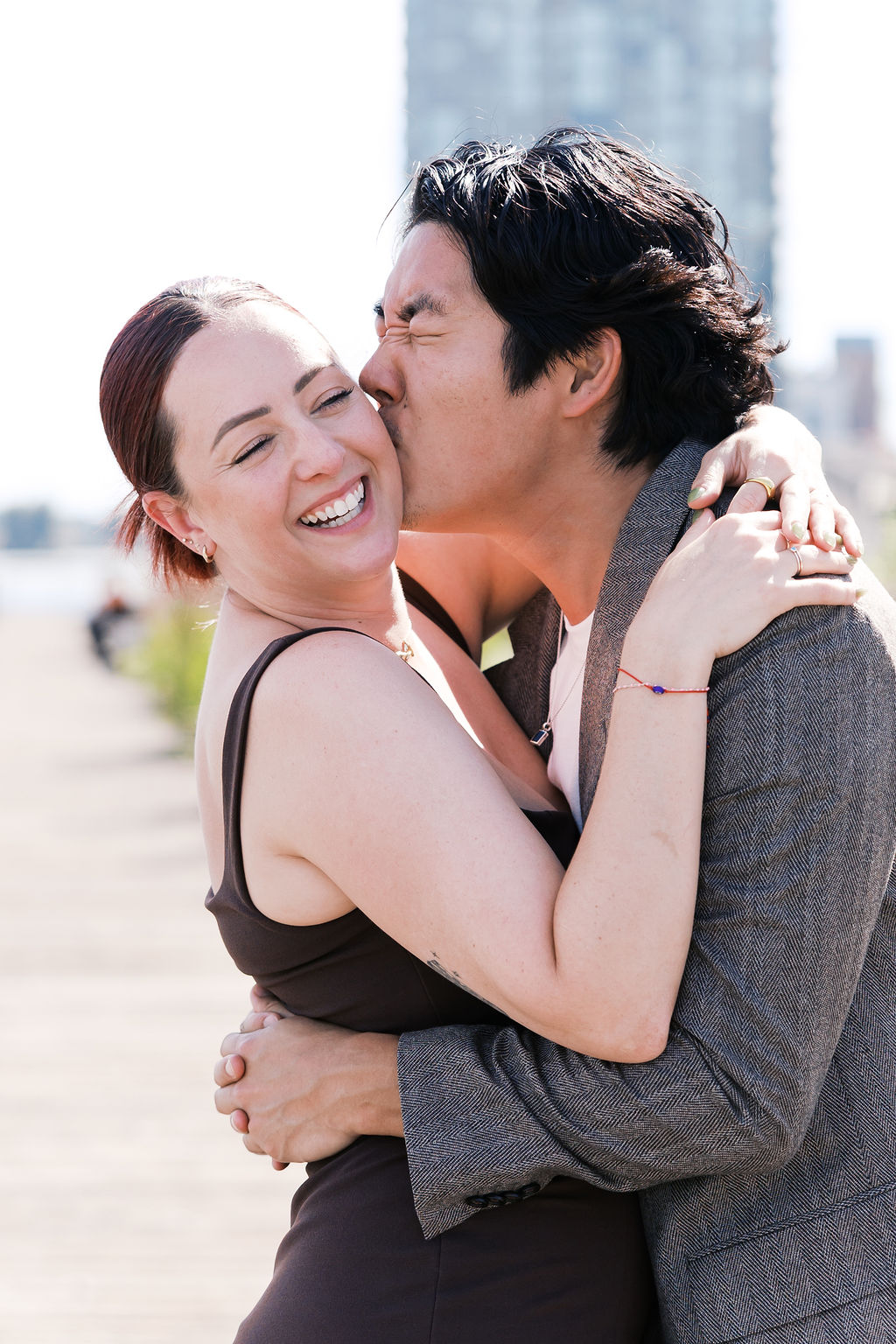 One partner kisses the other's cheek as they smile after the proposal.