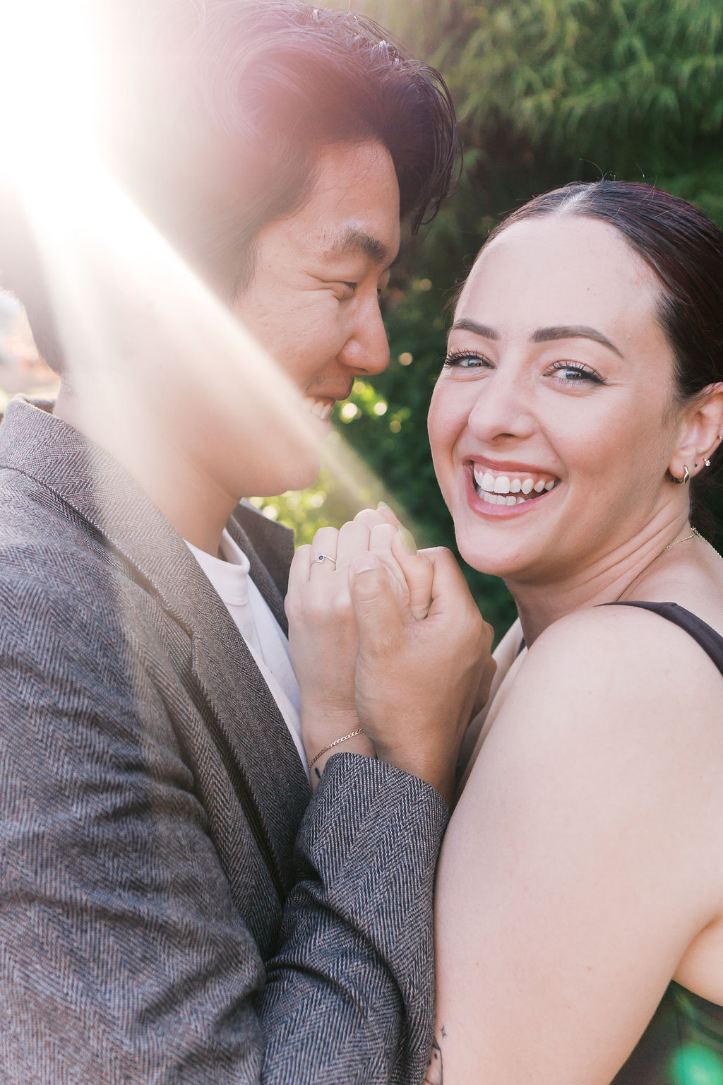 Close portrait of the couple holding hands, with the engagement ring visible in the foreground.