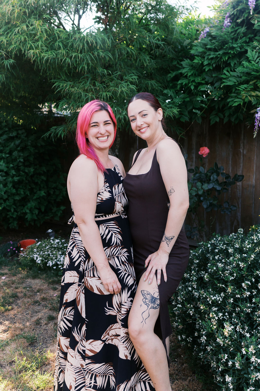 The newly engaged person poses with a friend in a garden after the celebration.