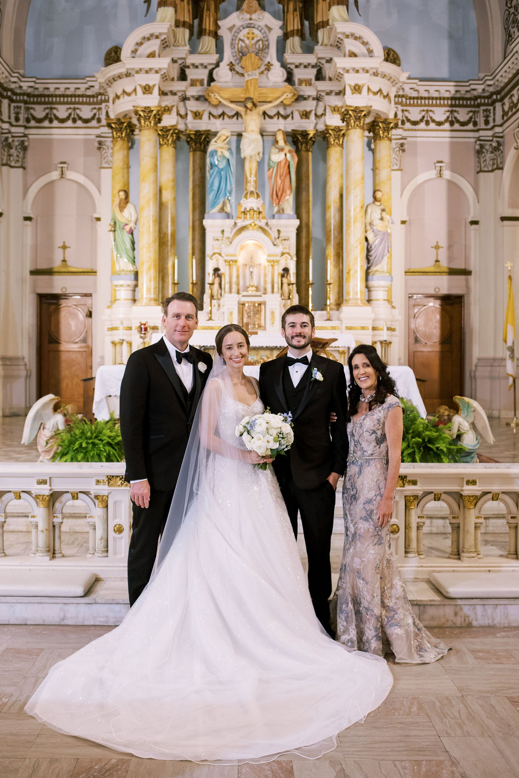 Bride and groom pose with two family members at the altar during traditional church wedding family formals.